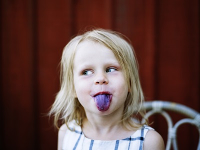 Flicka räcker ut tungan som är blå. 